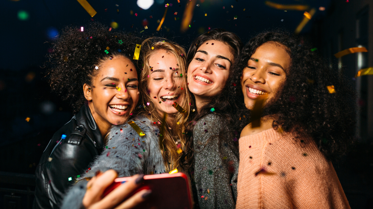 A group of four happy friends taking a selfie at a party to share on Recap.